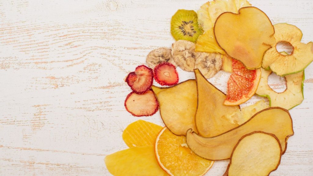 Dried pears, oranges, bananas, and strawberries laying on a counter.