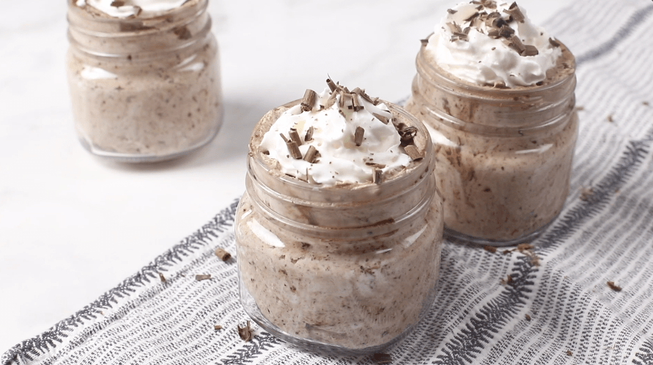 Chocolate mousse in small jars topped with whipped cream and shaved chocolate.