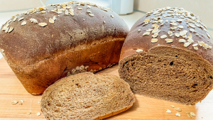 Two loaves of brown bread with one sliced