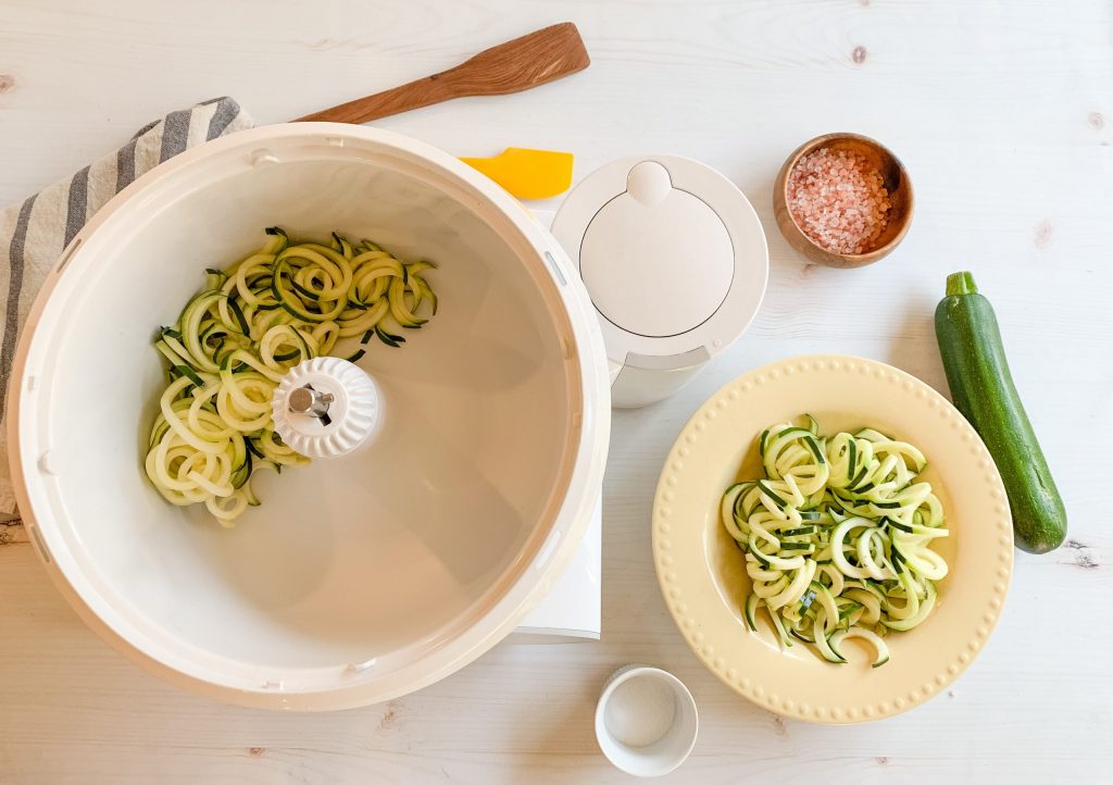 Bosch Universal Plus Mixer with Veggie Noodles in the bowl next to a plate of veggie noodles made out of zucchini