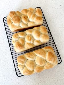 Three loaves of braided Swiss bread sitting on a cooling rack, view from the top.