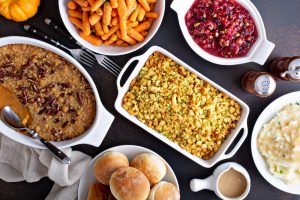 Thanksgiving meal on table, including stuffing, carrots, cranberries, rolls and gravy.